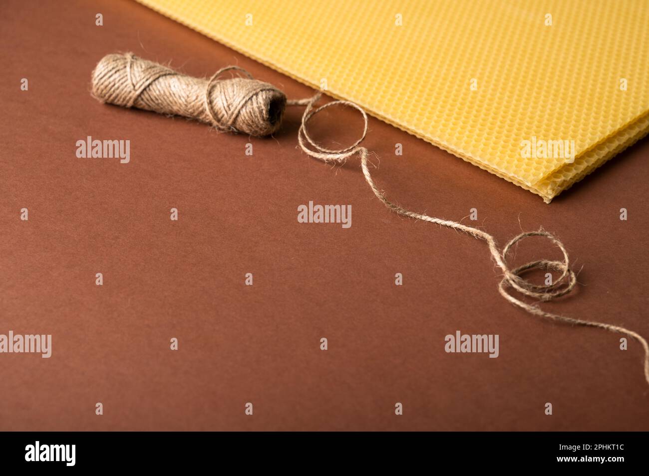 Beeswax candle sheets and jute thread on brown background
