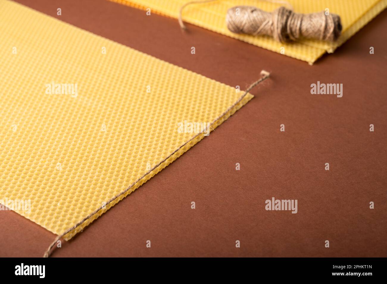 Beeswax candle sheets and jute thread on brown background