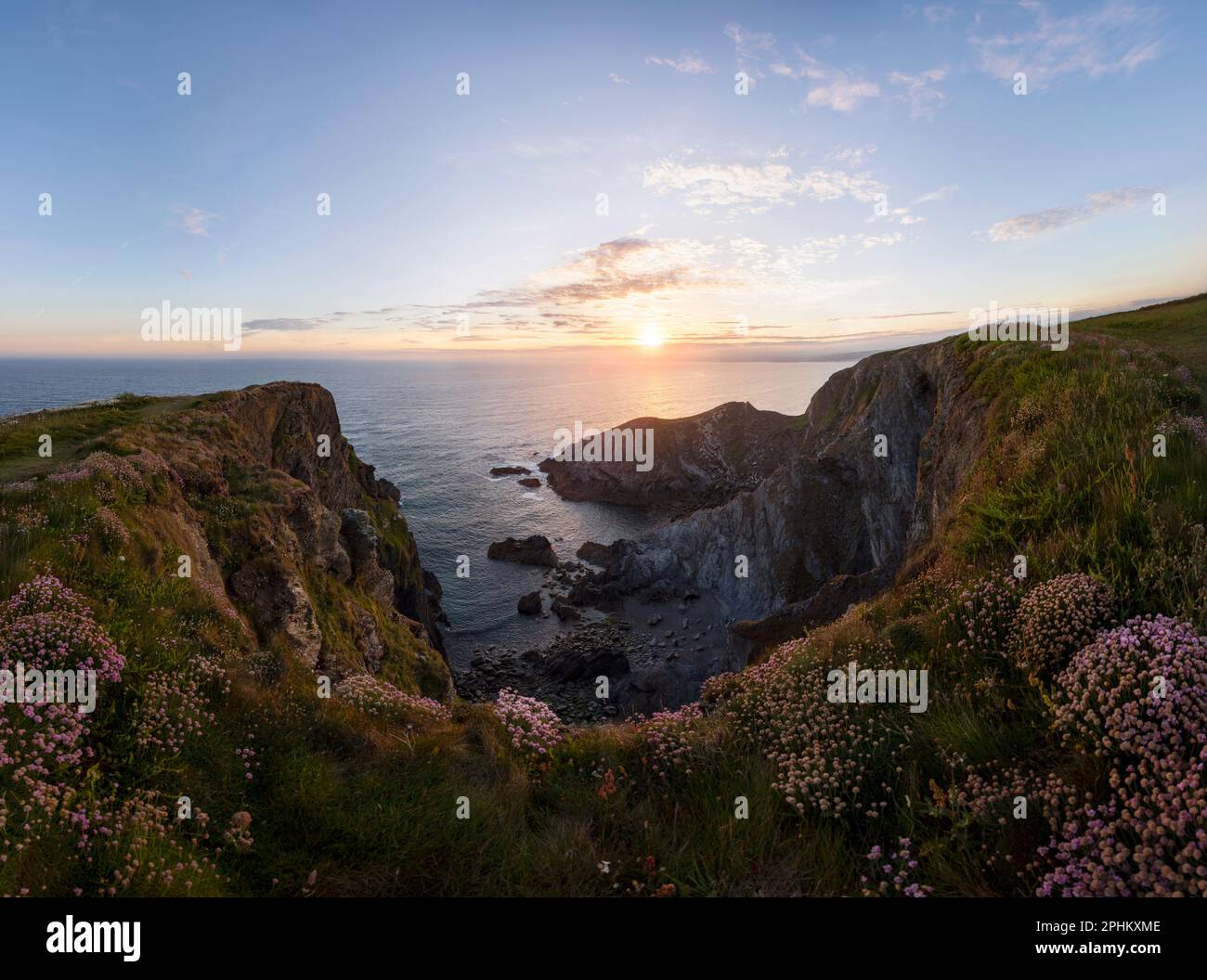 Sunset from Halzephron Cliffs on the Lizard Peninsula in Cornwall. Looking out over the rocks and wild flowers to the sea near Chuch Cove Stock Photo