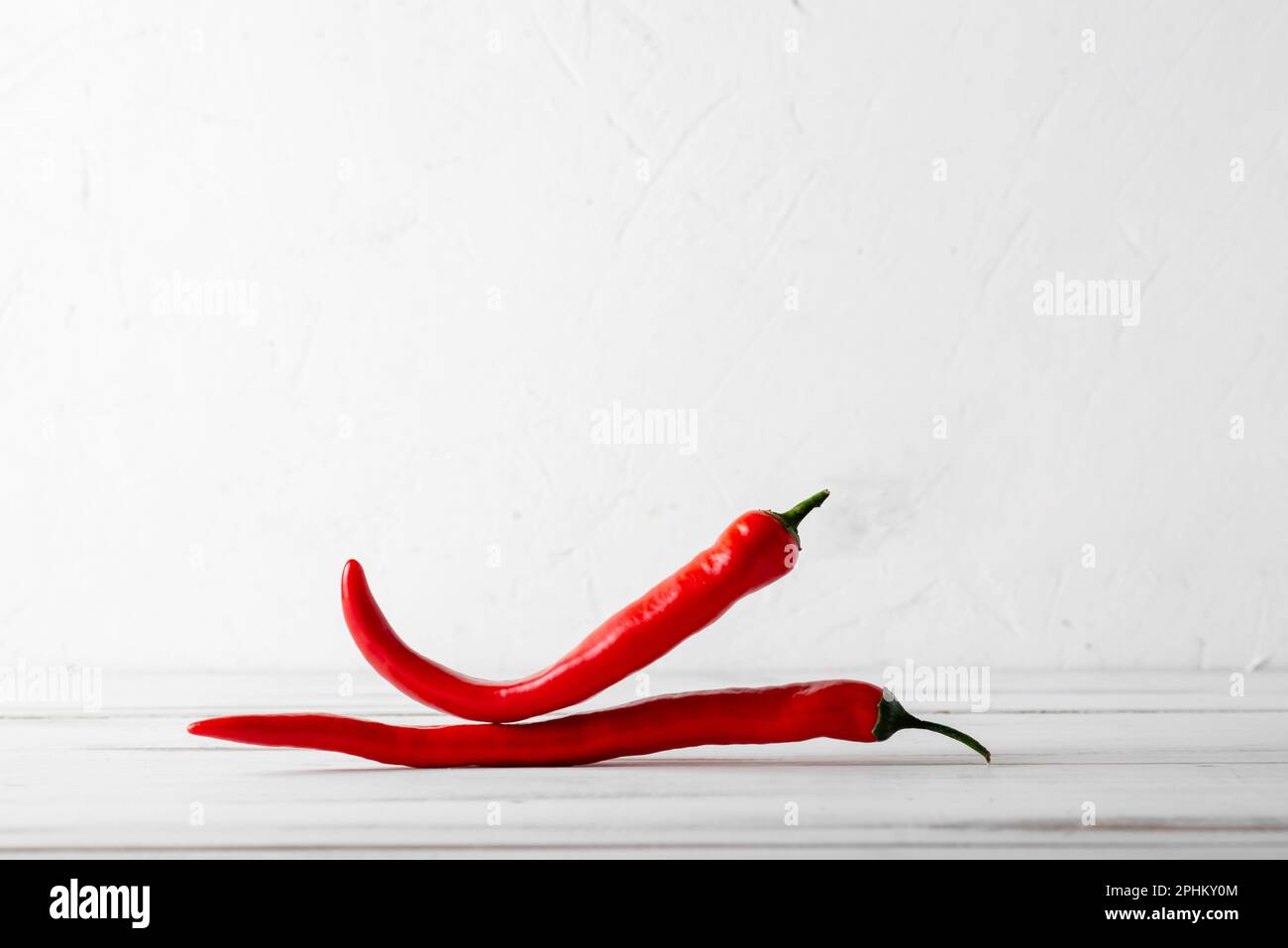 Red hot chili peppers on a white wooden background Stock Photo - Alamy
