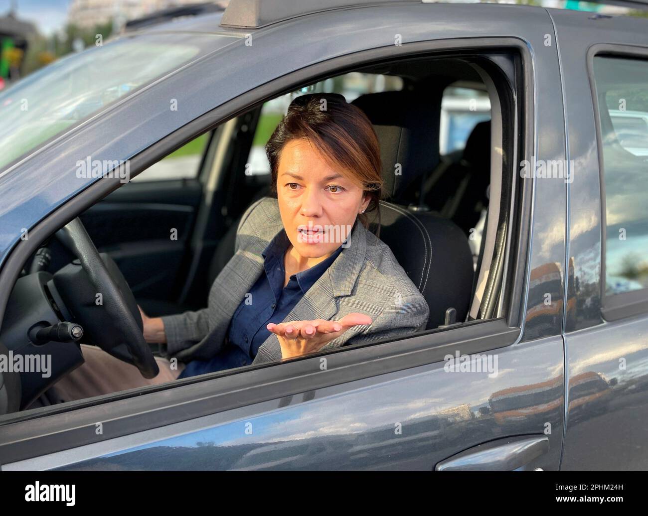 Close up of Caucasian pretty woman sitting in auto looking through window with pretentious face expression. Traffic. Woman driver unhappy with road Stock Photo
