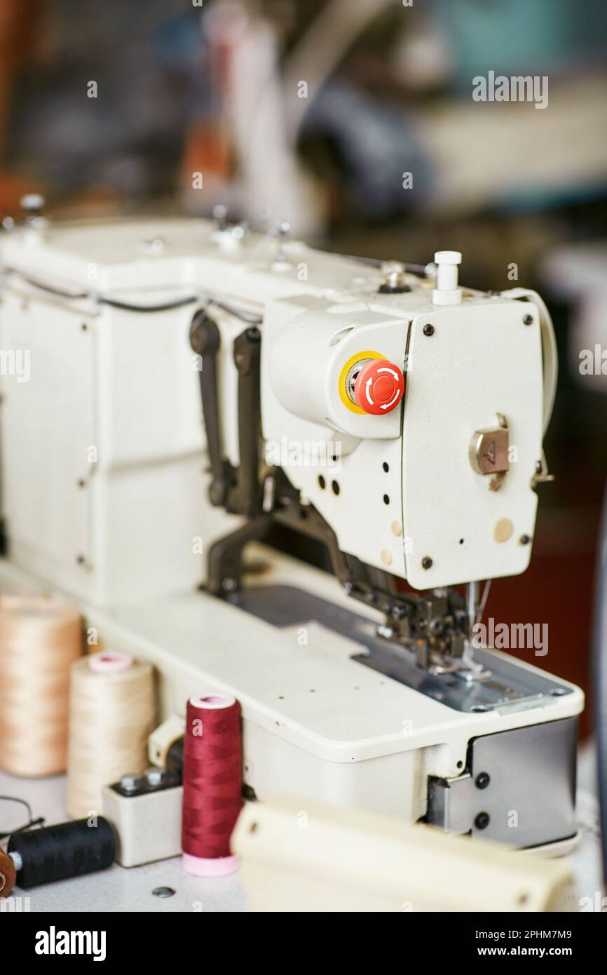 White sewing machine with threads nearby without workers Stock Photo