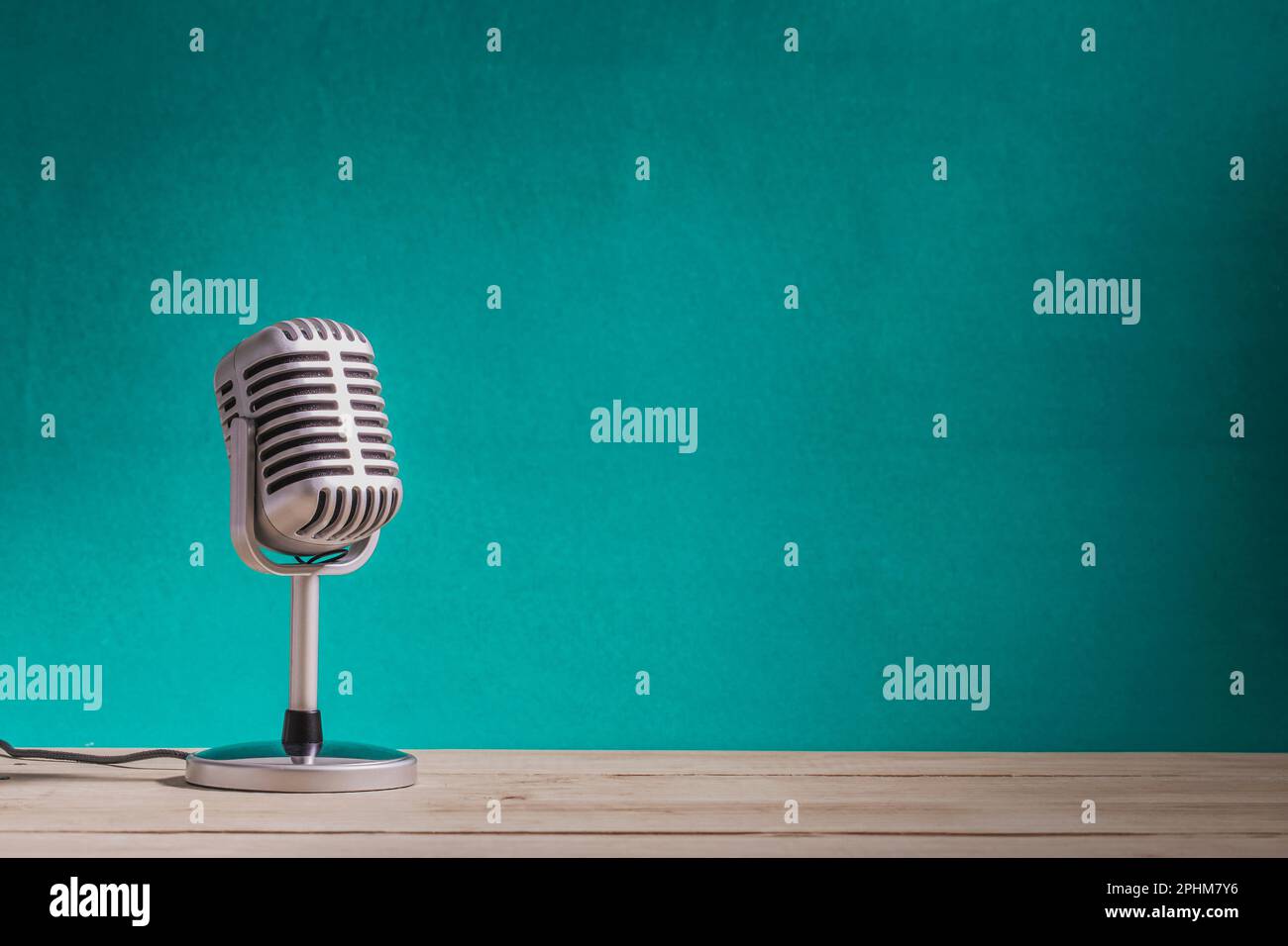 Retro microphone on wooden table with green wall background Stock Photo