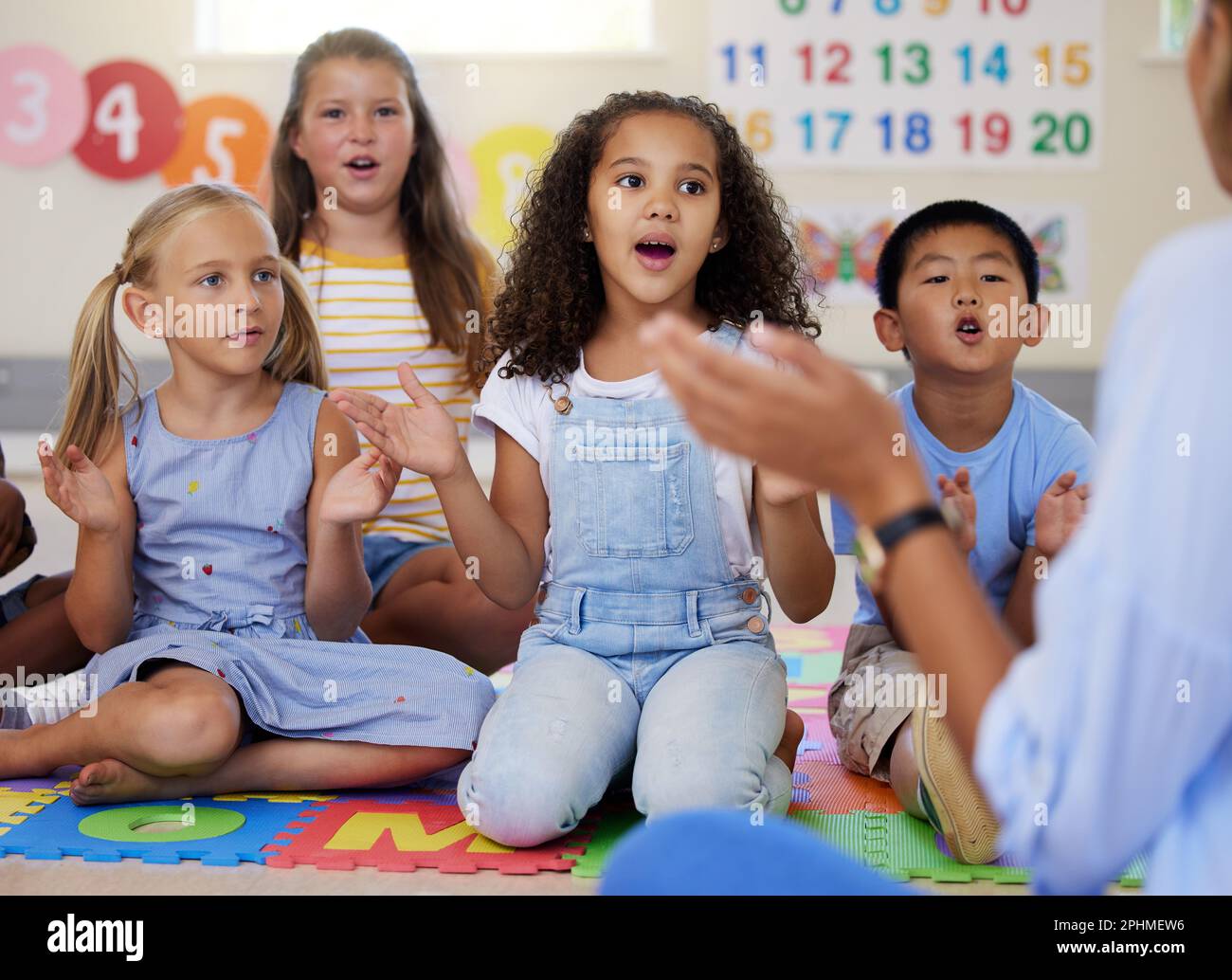 Teacher, singing or kids in classroom learning a song together in preschool for voice development. Children daycare, vocal or young students in poem Stock Photo