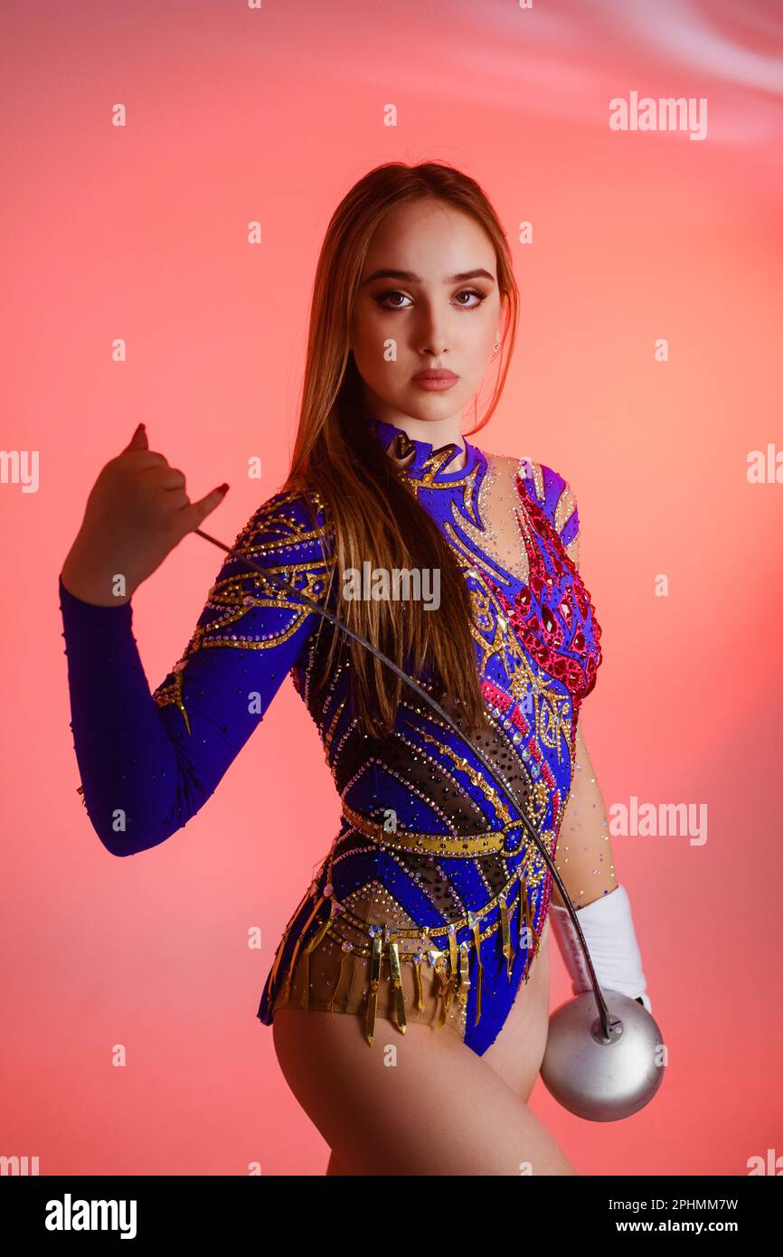 Girl gymnast wears a gymnastic leotard holding a sword in her hands on