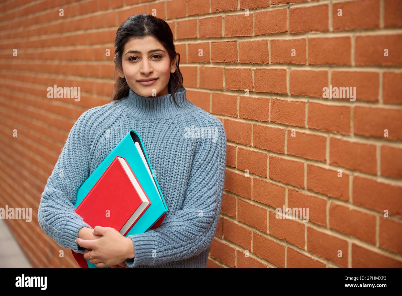 Portrait Of Smiling Female College Or University Student Outside Campus Building With Books Stock Photo