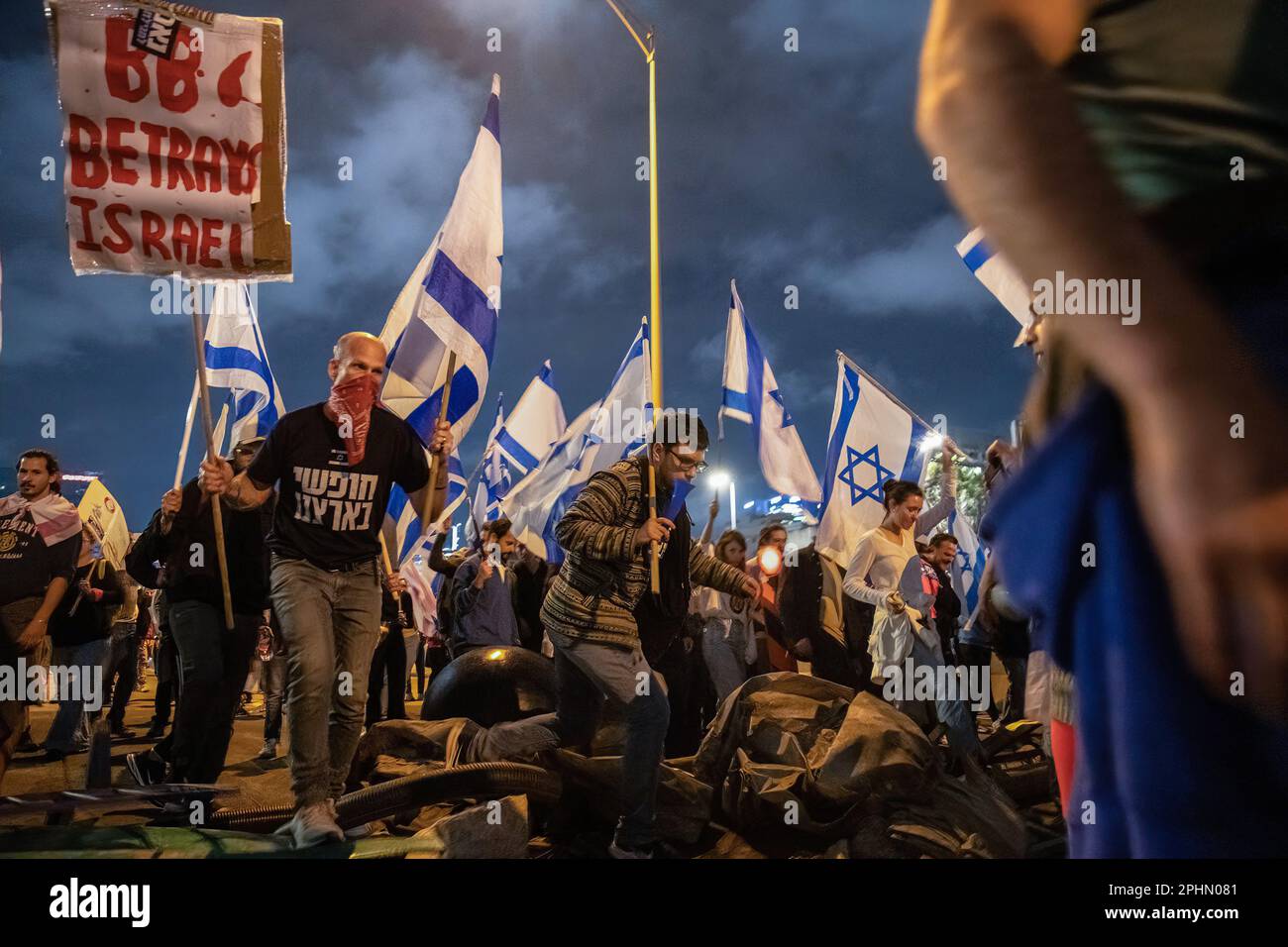 Tel Aviv, Israel. 25th Mar, 2023. Anti-reform demonstrators cross a barricade as they hold signs and wave Israeli flags during an anti-reform demonstration in Tel Aviv. Over 230,000 people protest in Tel Aviv against Netanyahu's far-right government and its controversial legal reform. (Credit Image: © Matan Golan/SOPA Images via ZUMA Press Wire) EDITORIAL USAGE ONLY! Not for Commercial USAGE! Stock Photo