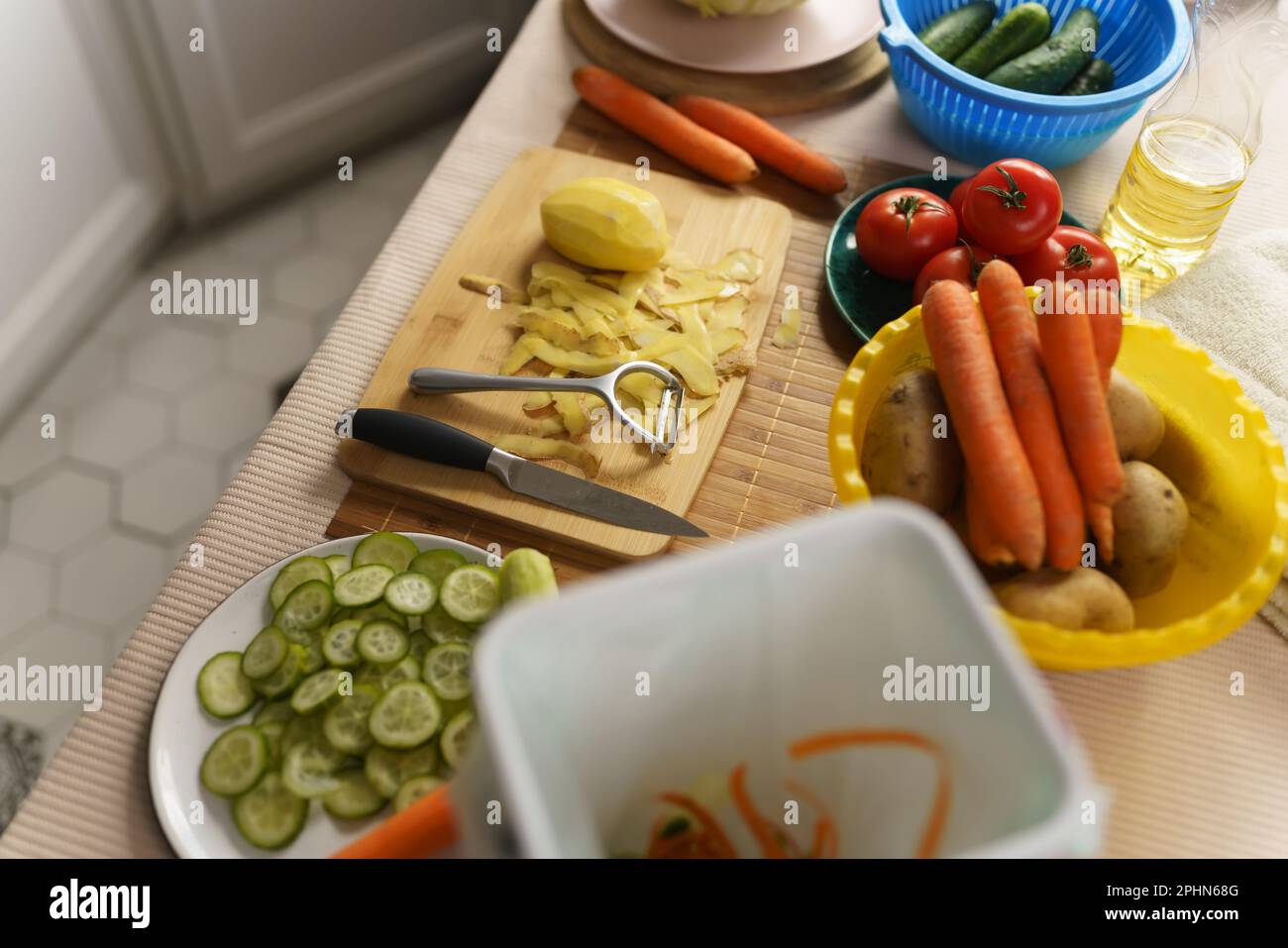 Kitchen table with vegetables and peels. Recycle organic food waste in a compost bin at home. Bokashi container for compostable leftovers Stock Photo