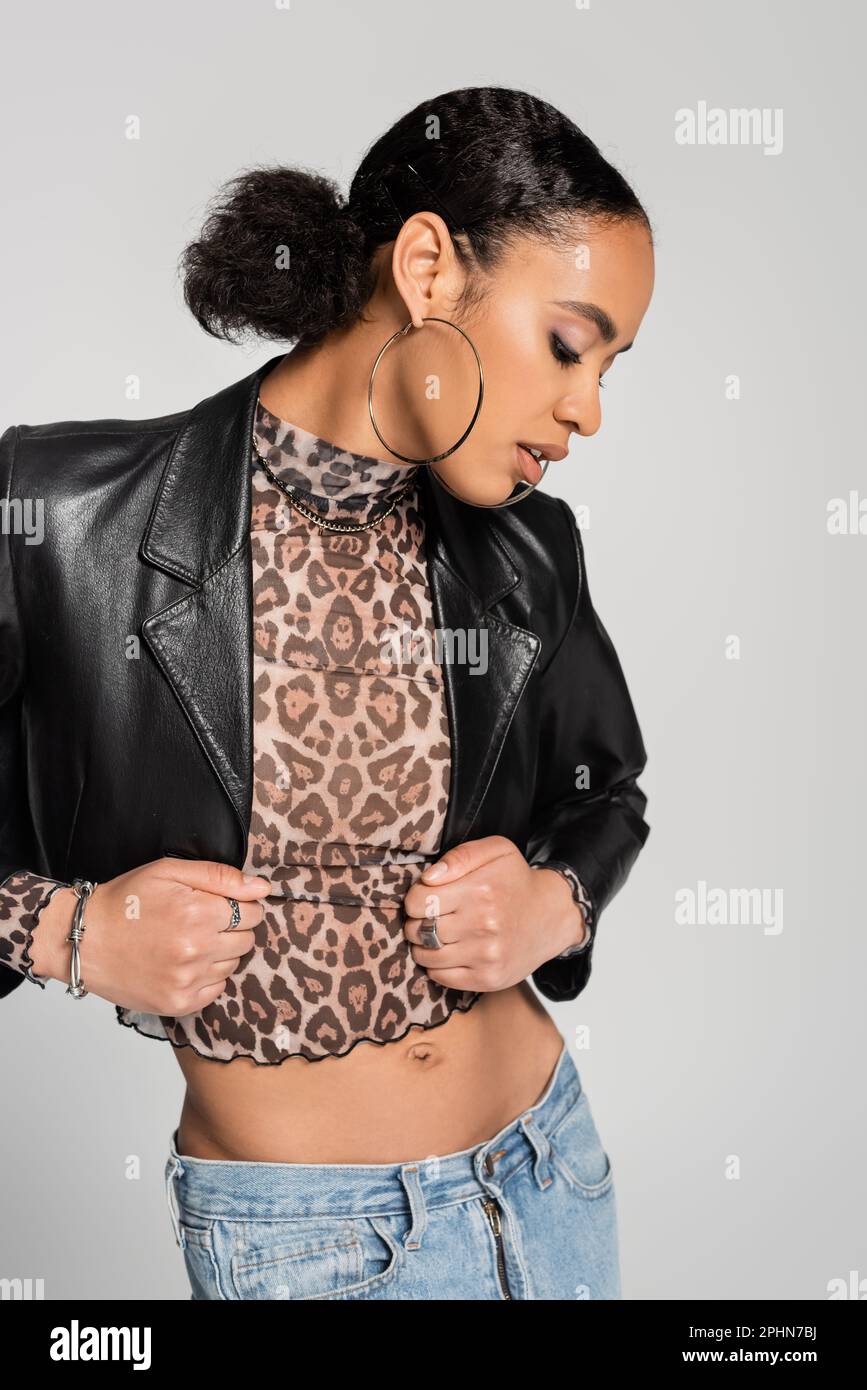 fashionable african american woman in black cropped jacket adjusting turtleneck with animal print isolated on grey,stock image Stock Photo