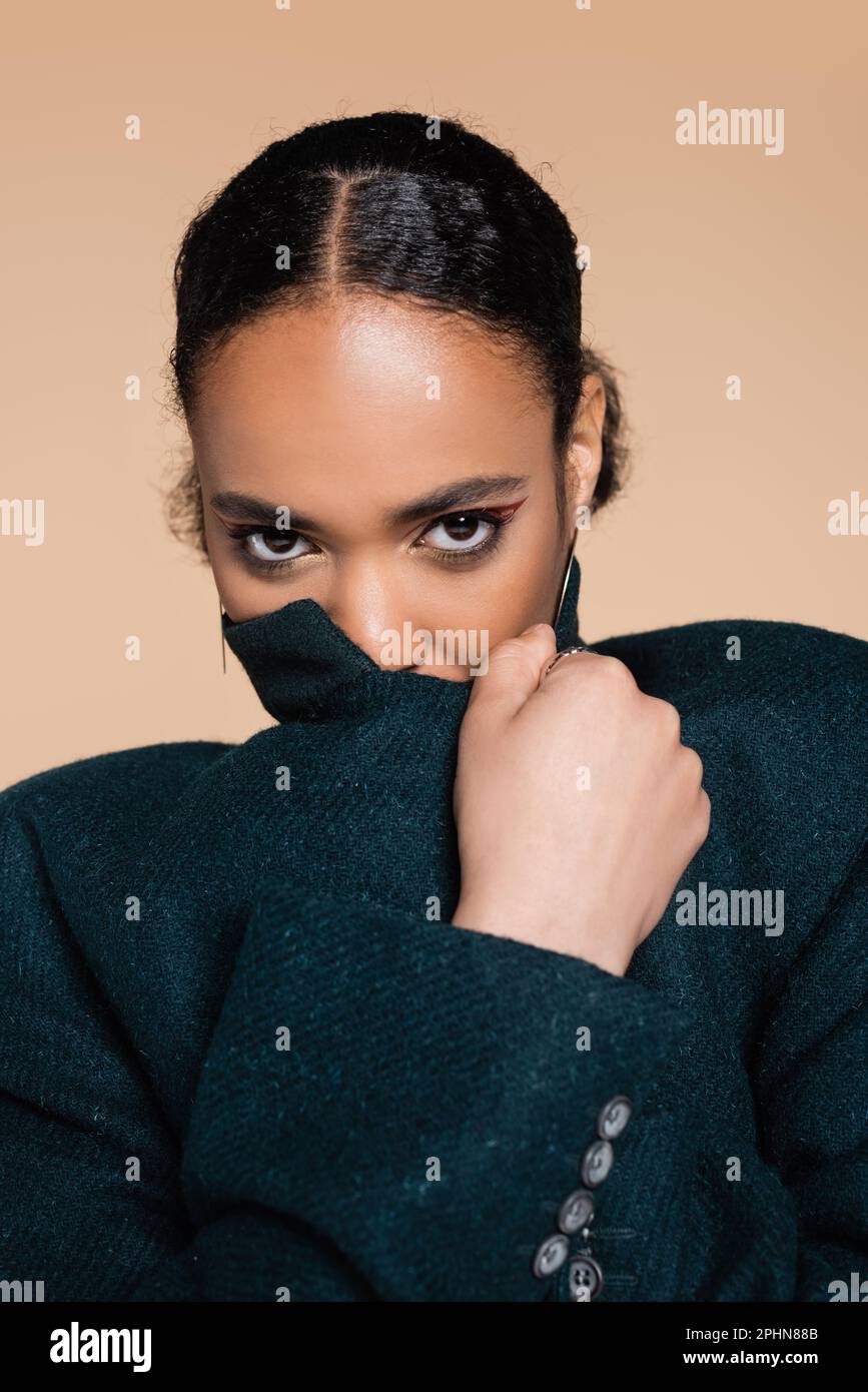 portrait of young african american woman covering face with collar of ...