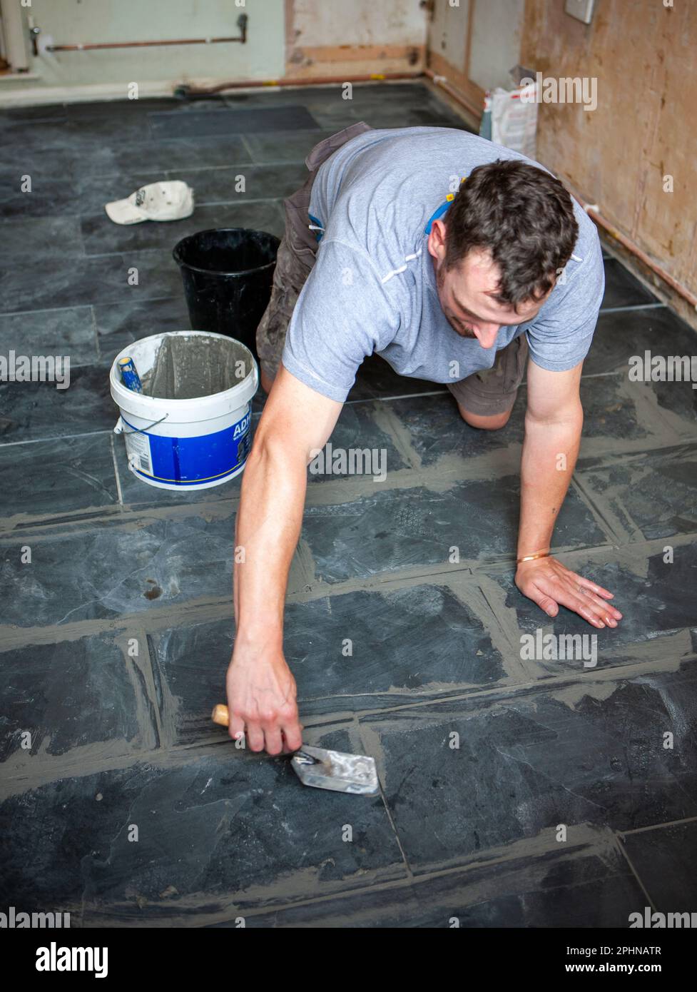 Kitchen Fitters Grouting the Floor. A tiler applying grout to a newly