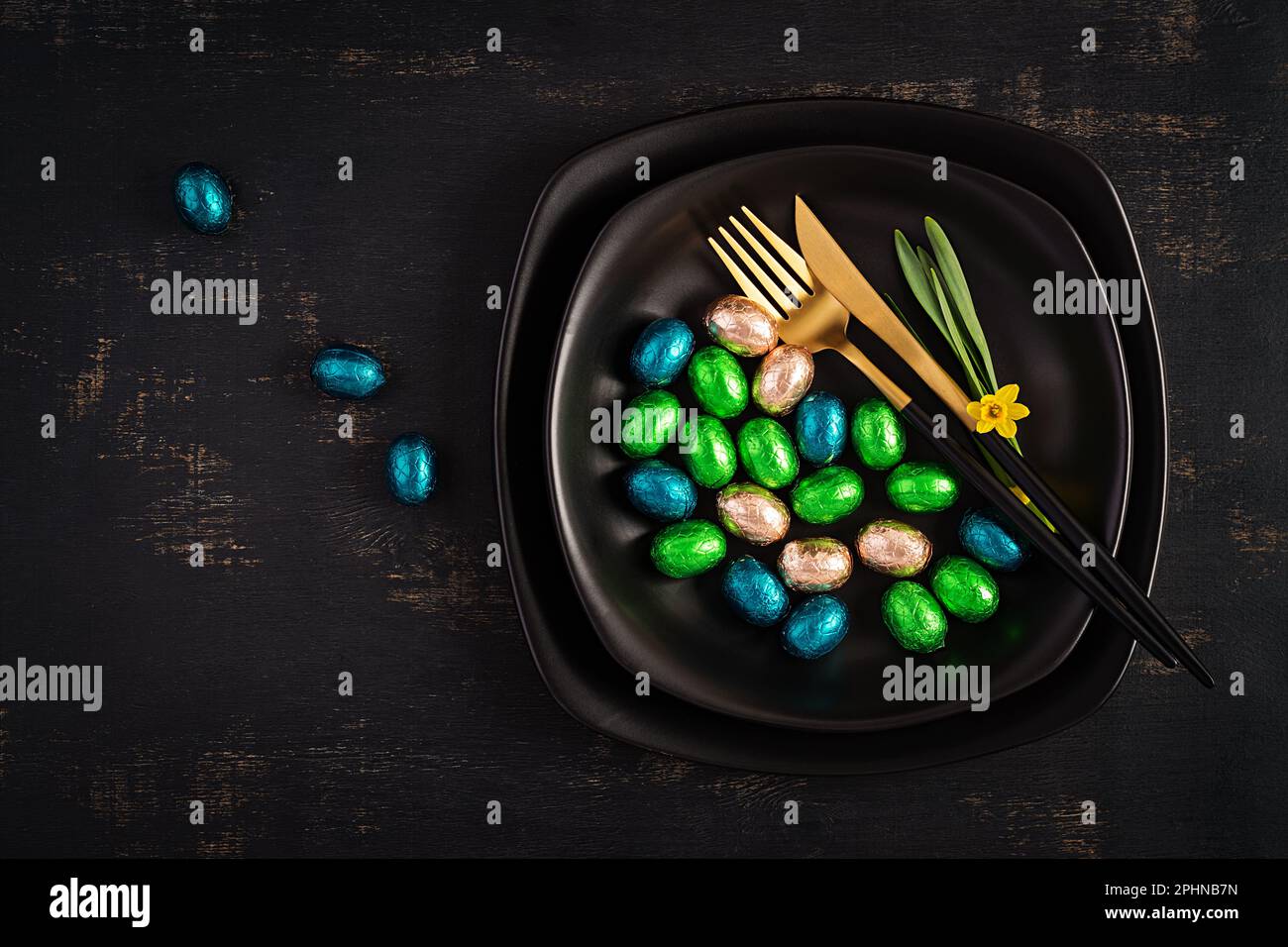 Happy Easter. Table setting for Easter holiday. Easter chocolate eggs and cutlery on dark background. Top view, flat lay Stock Photo