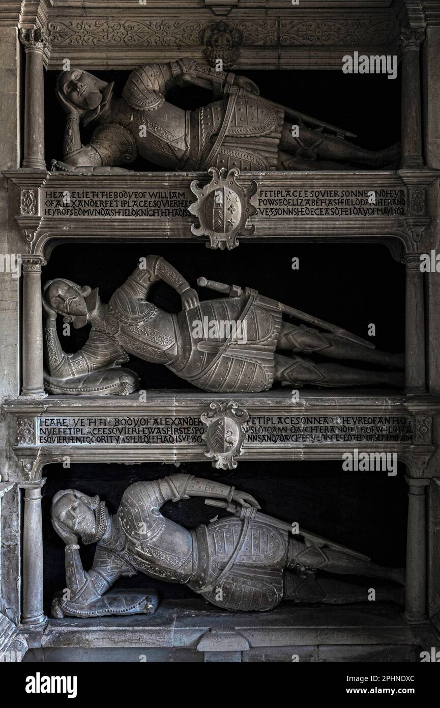 On the shelf: Fettiplace family 1500s and 1600s patriarchs, wearing Tudor armour, lie propped stiffly on elbows in a unique tiered chancel monument in St Mary’s Parish Church in the Windrush Valley Cotswolds village of Swinbrook, Oxfordshire, England, UK.  The house built on the site of their mansion belonged to Lord and Lady Redesdale, who lie in the churchyard with four of their controversial daughters: Pamela, Nancy, Diana and Unity Mitford. Stock Photo