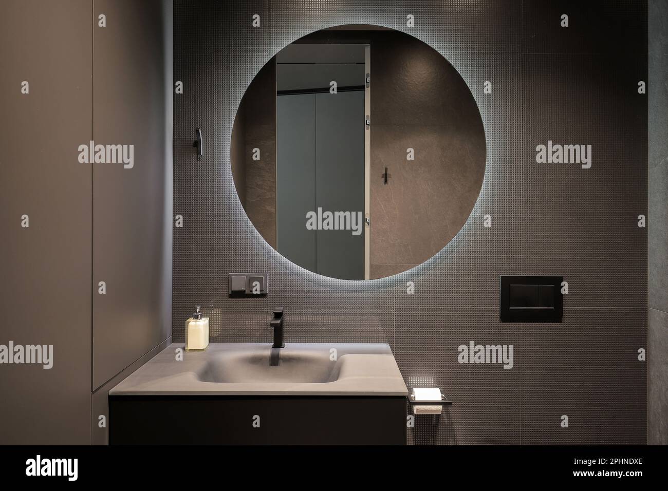 Illuminated round mirror in modern dark bathroom interior Stock Photo - Alamy