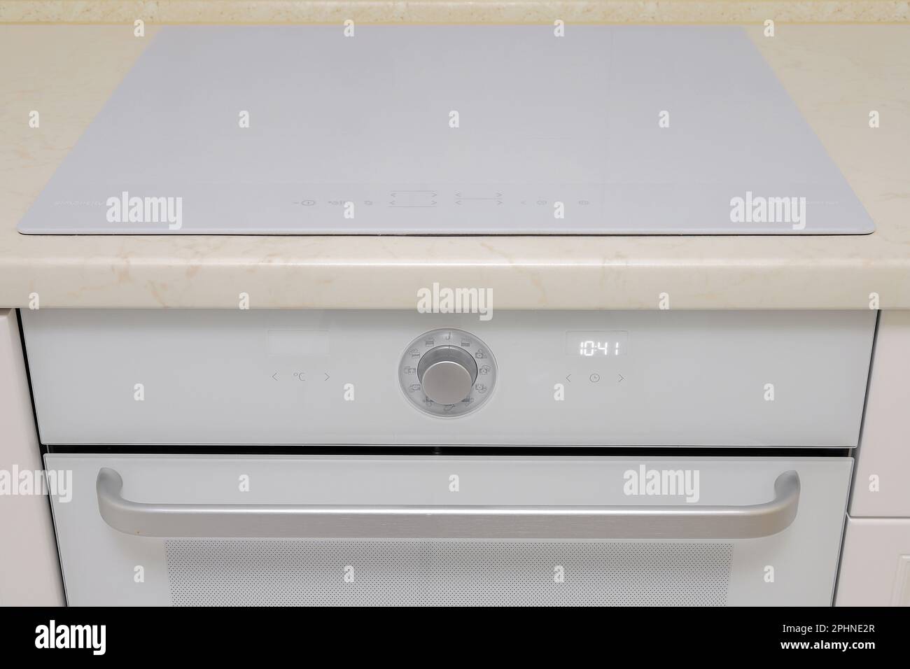 White electric stove and electric oven built into the kitchen furniture