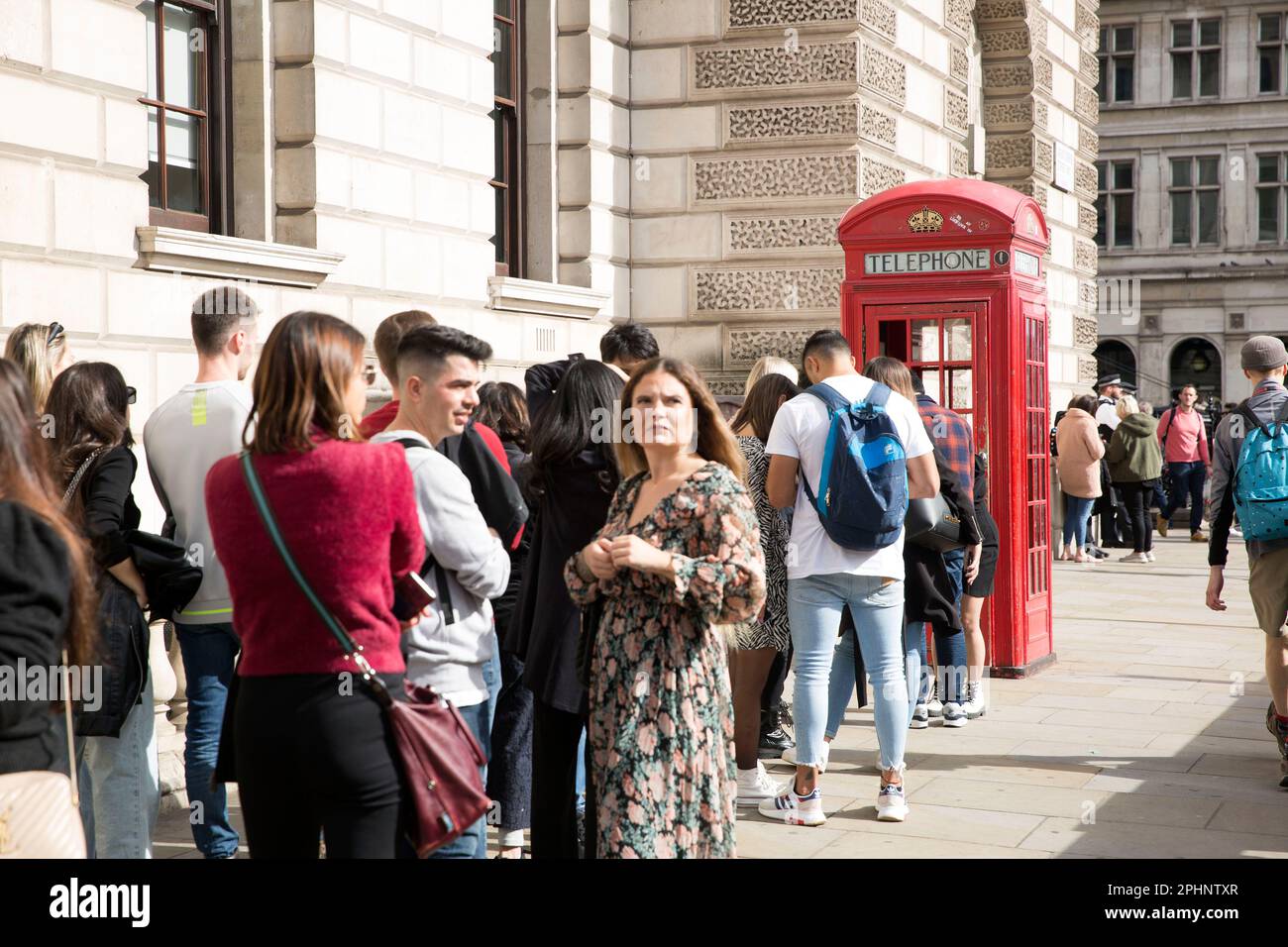 People queue to take photographs next to a red telephone box in