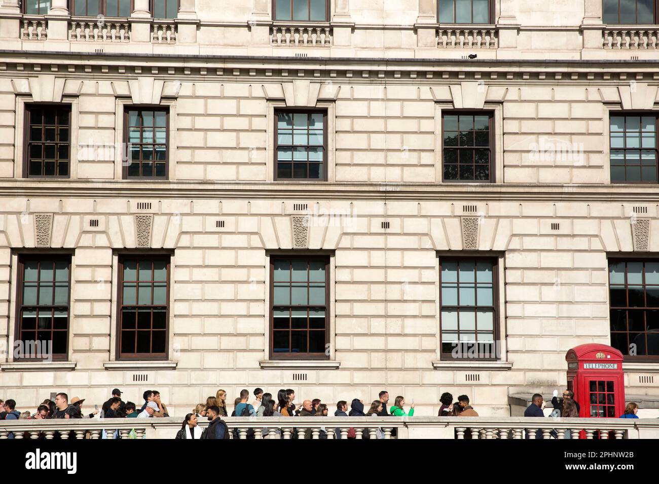 People queue to take photographs next to a red telephone box in
