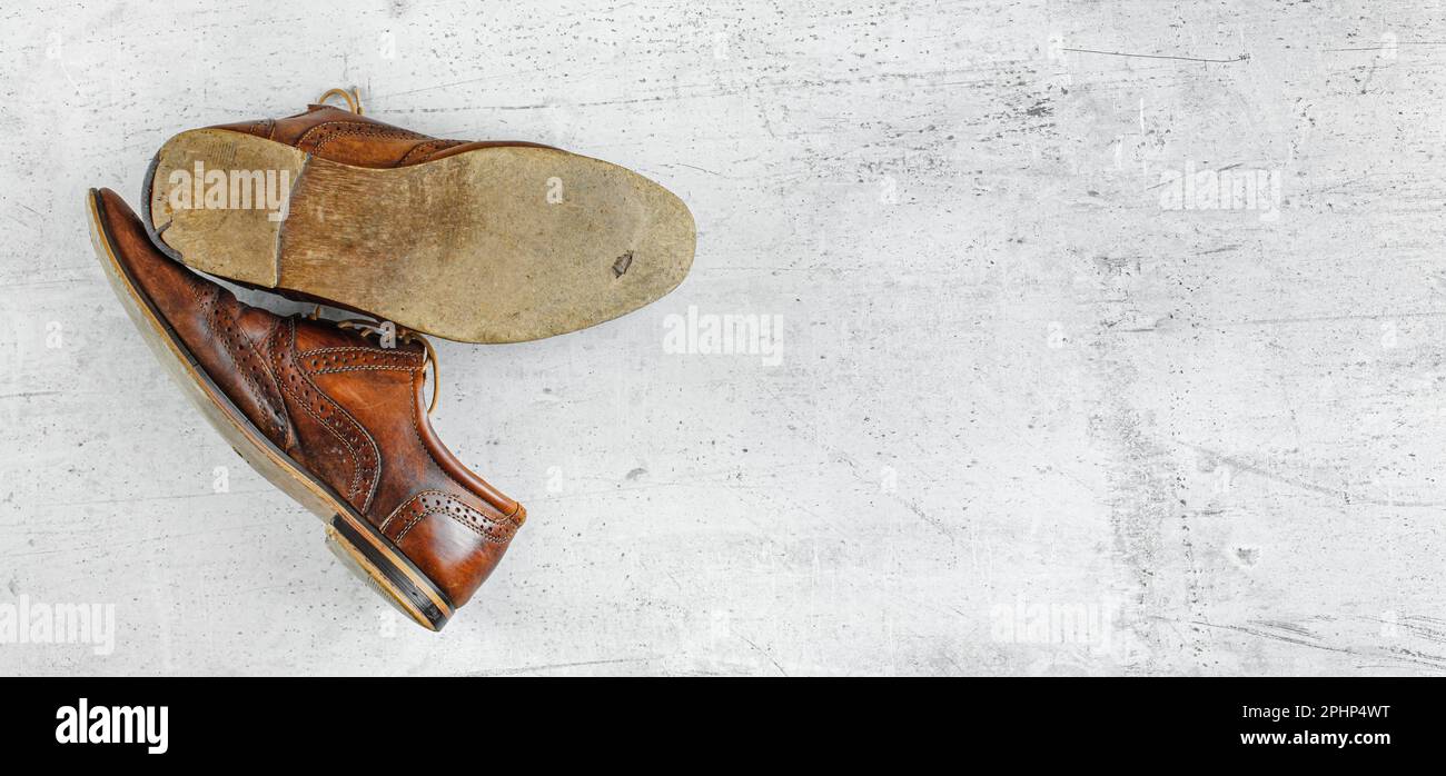 Top down view, worn classic dark brown brogue shoes on white board. Wide banner with space for text right Stock Photo