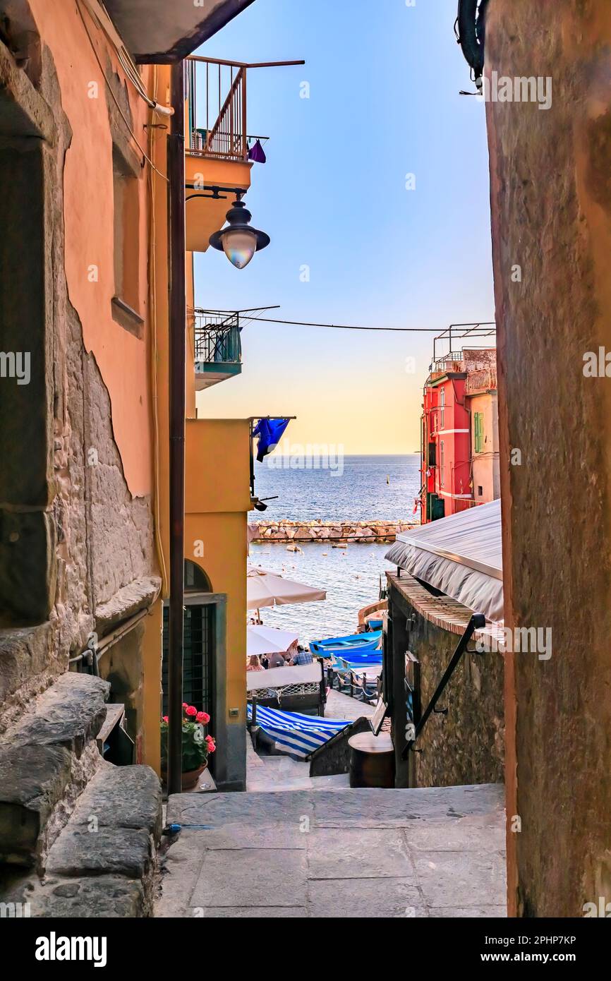 View onto the Mediterranean Sea with traditional boats and colorful houses in old town of Riomaggiore in Cinque Terre, Italy Stock Photo