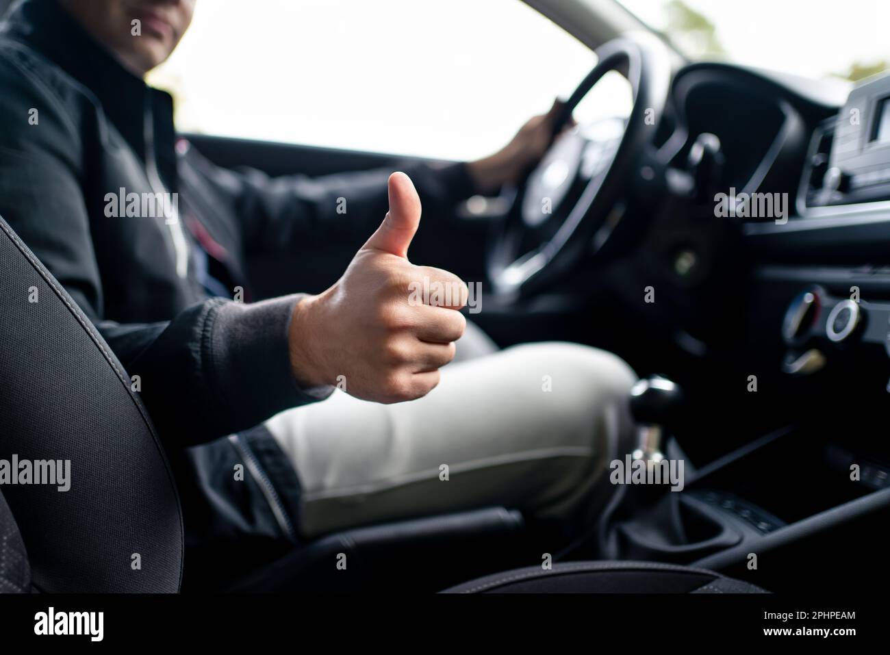 Happy driver in car, thumbs up. Man driving. Smiling positive new vehicle buyer and owner. Good customer service in taxi, dealership, insurance. Stock Photo