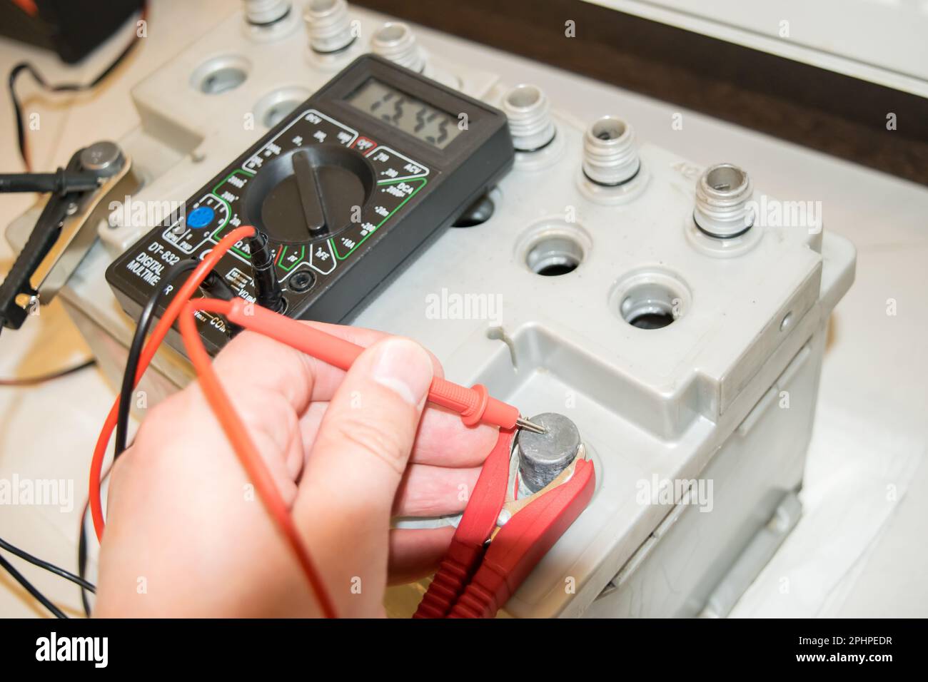 Car battery charging. Gray battery with caps unscrewed, charger cables