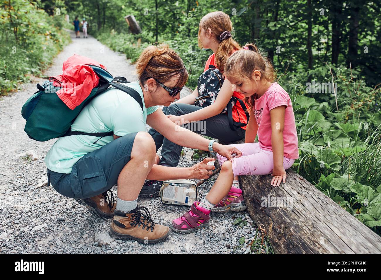 Mother dressing the wound on her little daughter's knee with medicine