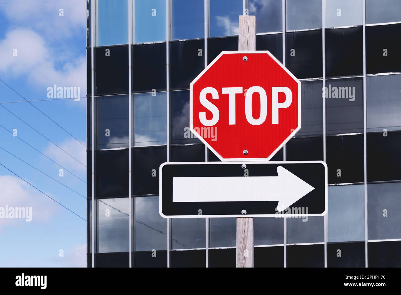 Stop sign and directional arrow in front of office building Stock Photo
