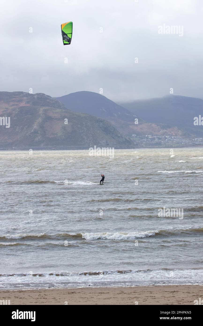 A single Kitesurfer with board, harness and foil enjoying the thrills of surfing in challenging seas off the West shore of Llandudno, North Wales Stock Photo