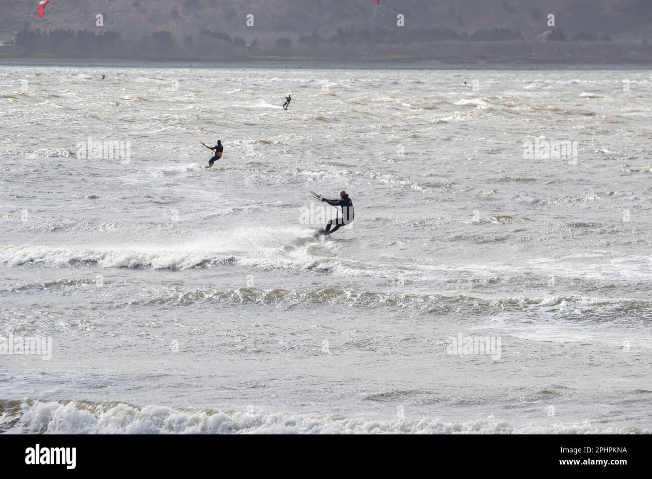 Kitesurfers enjoying the thrills of surfing in windy and choppy seas off Llandudno's west shore in challenging conditions Stock Photo