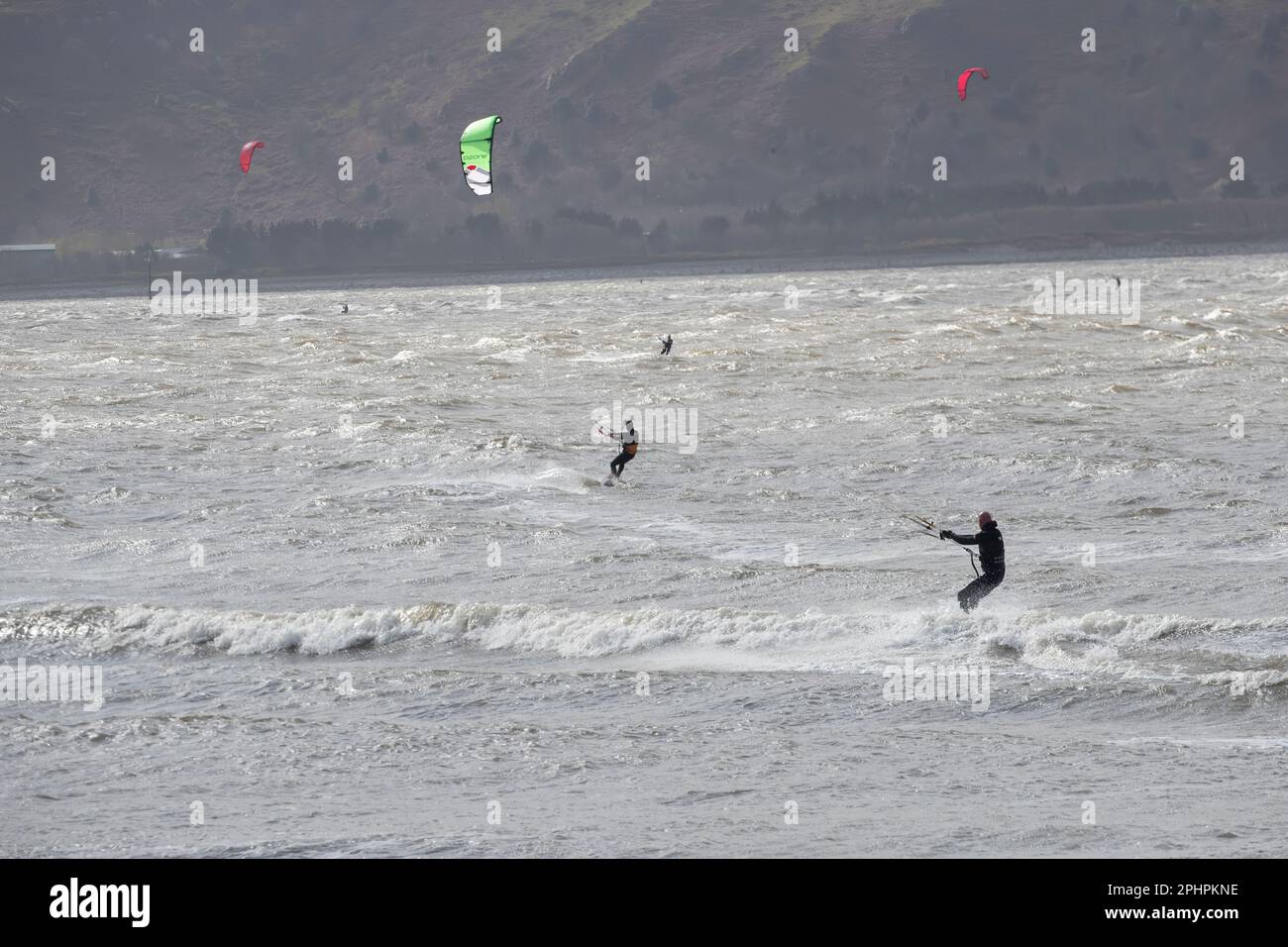 Kitesurfers enjoying the thrills of surfing in windy and choppy seas off Llandudno's west shore in challenging conditions Stock Photo