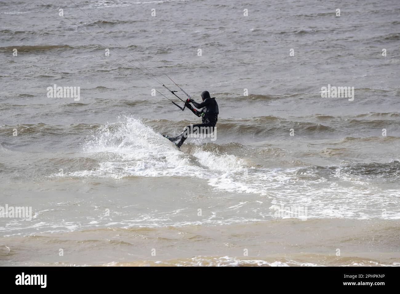 Kitesurfer enjoying the thrills of surfing on choppy and wavy water on the West shore of Llandudno in windy conditions Stock Photo