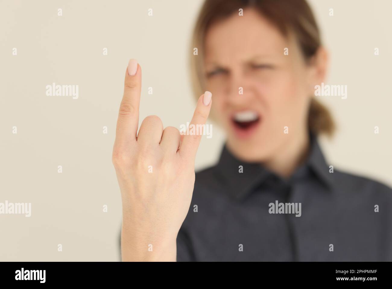 Blurry screaming woman shows horns gesture with fingers Stock Photo