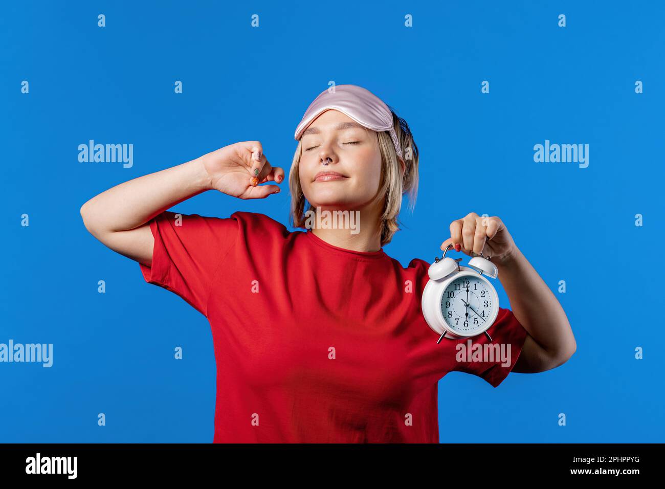 Woken up by alarm clock sleepy girl. Blue background. Early 6 o'clock