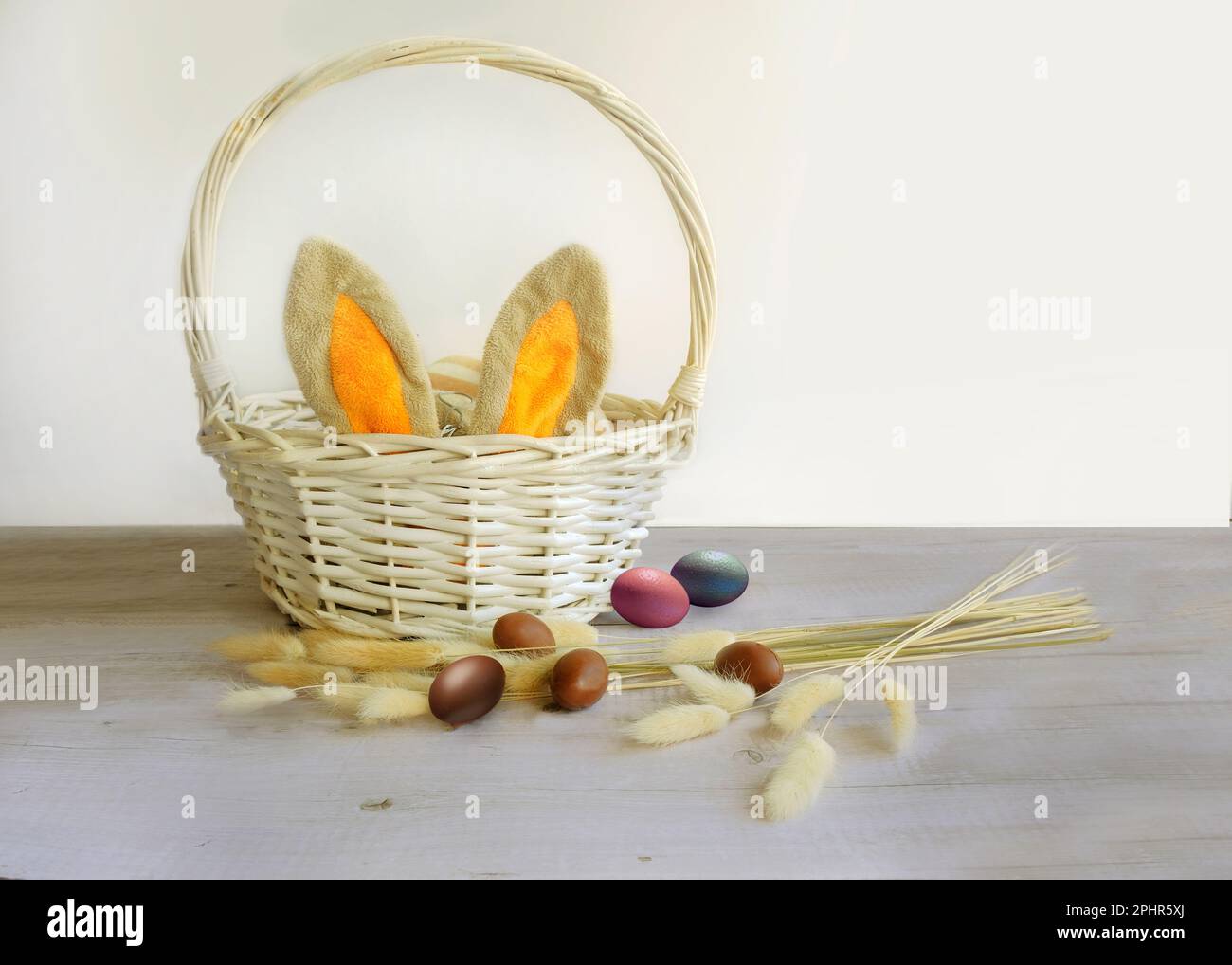 easter eggs and a white basket with rabbit ears Stock Photo