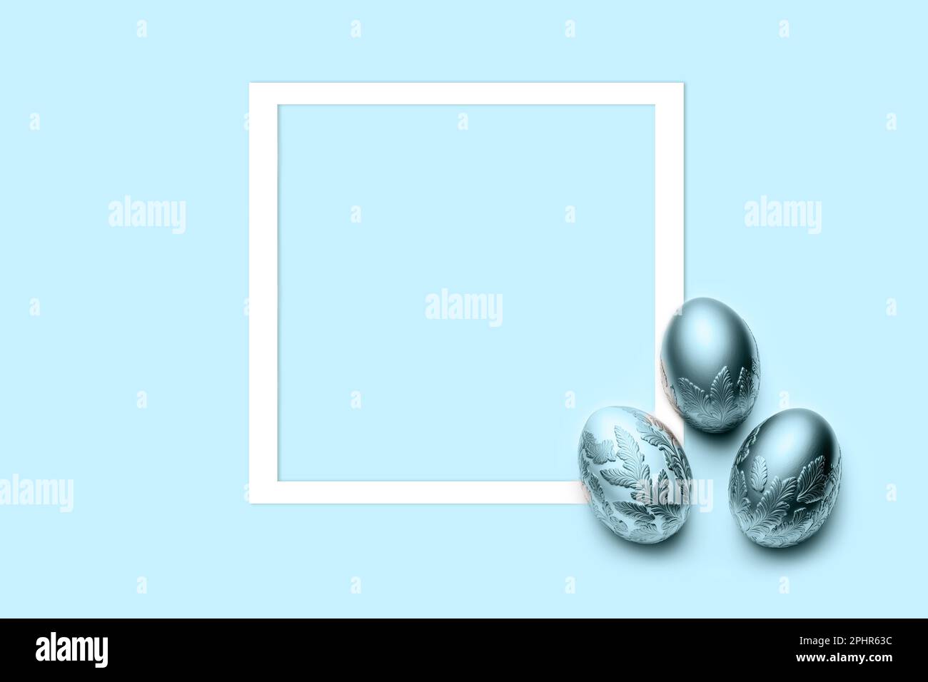 three blue eggs with frame on blue background. Flat lay, top view, copy space. Stock Photo