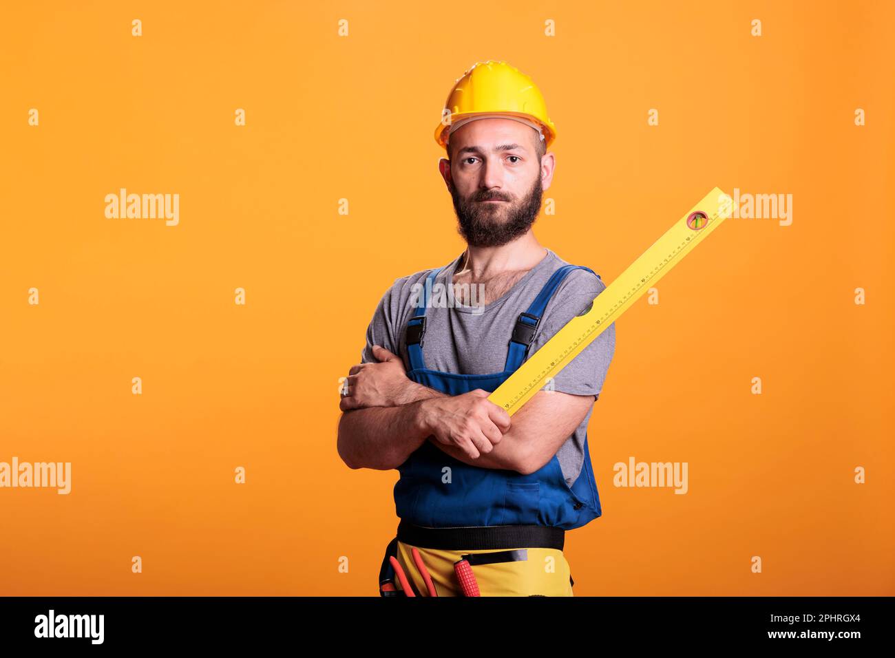 Construction worker holding water level ruler in studio, posing with ...