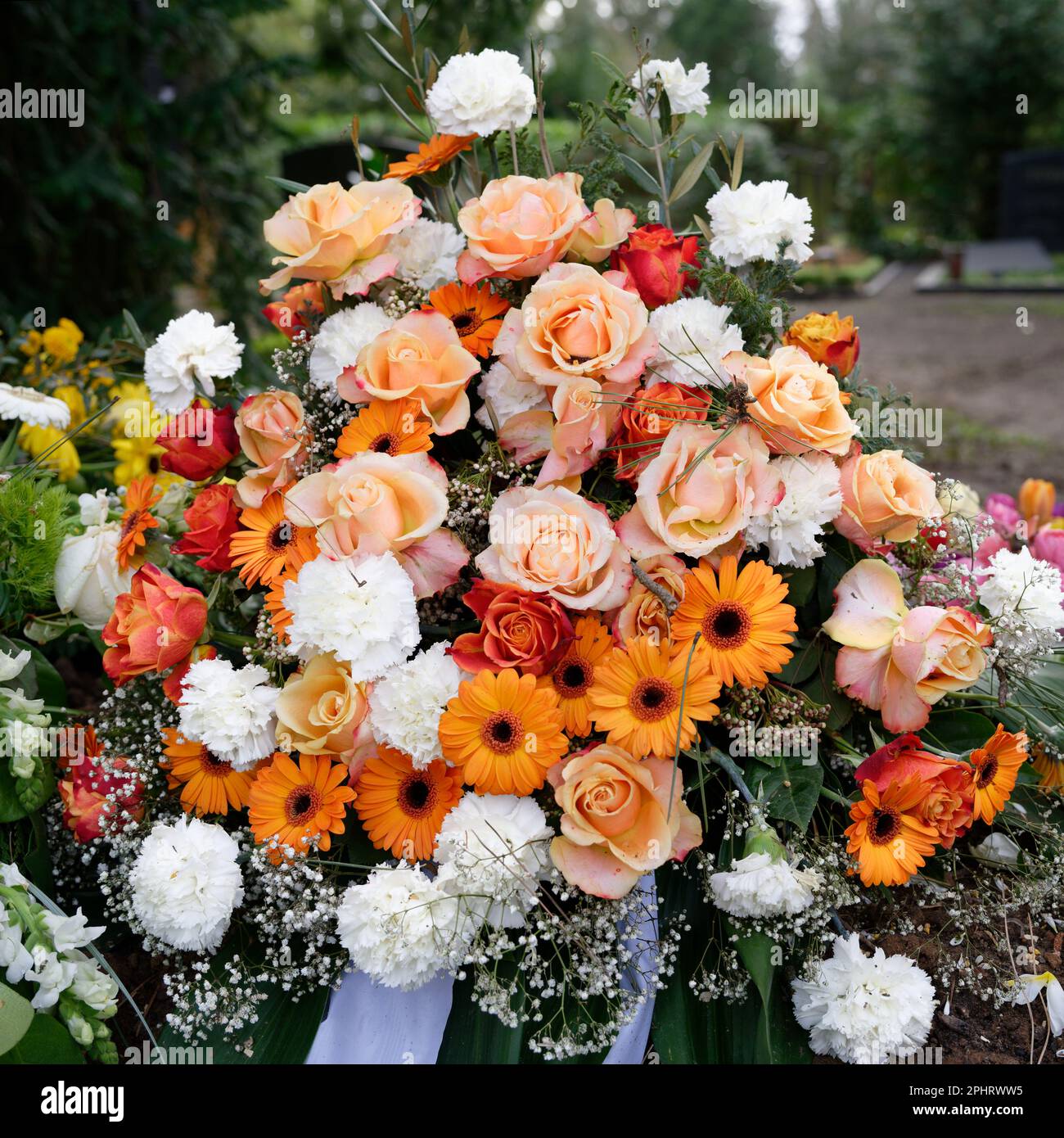 stylish funeral flowers of white carnations, orange gerbera and red and