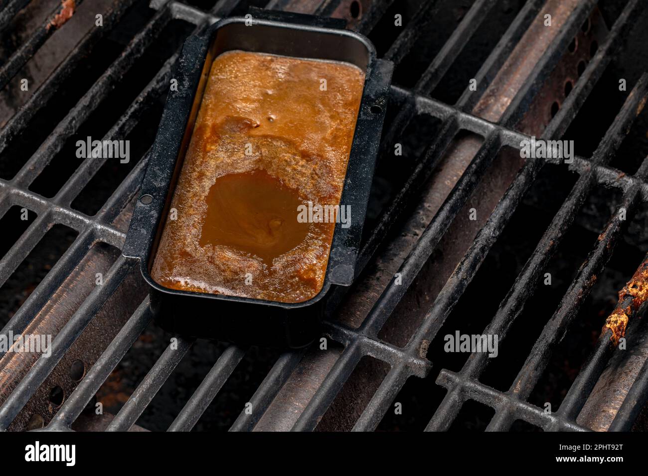 BBQ grill drip pan full of grease and fat. Barbeque grilling, cleaning and food safety concept. Stock Photo