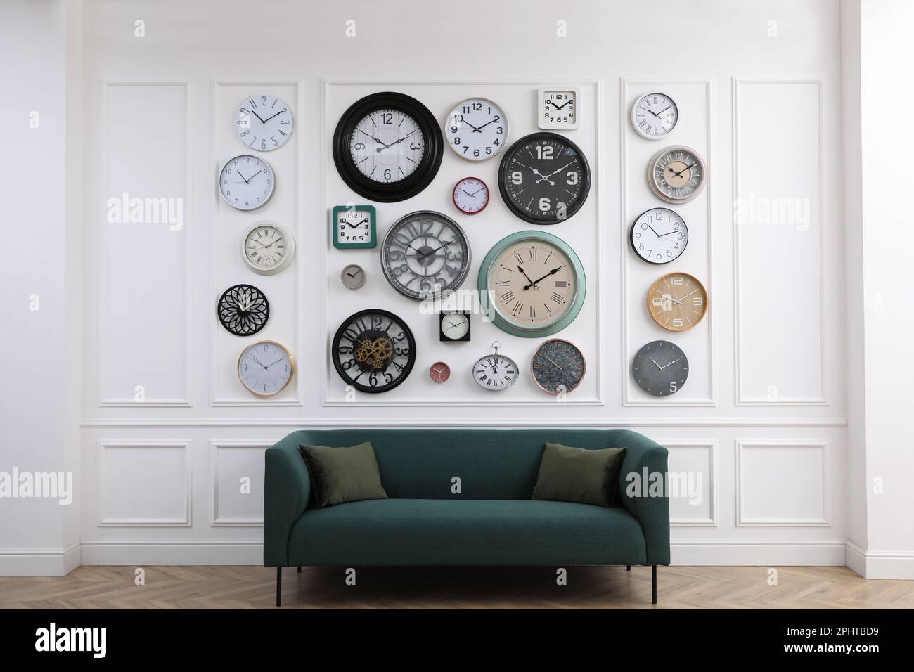 Collection of different clocks and comfortable sofa in stylish room ...