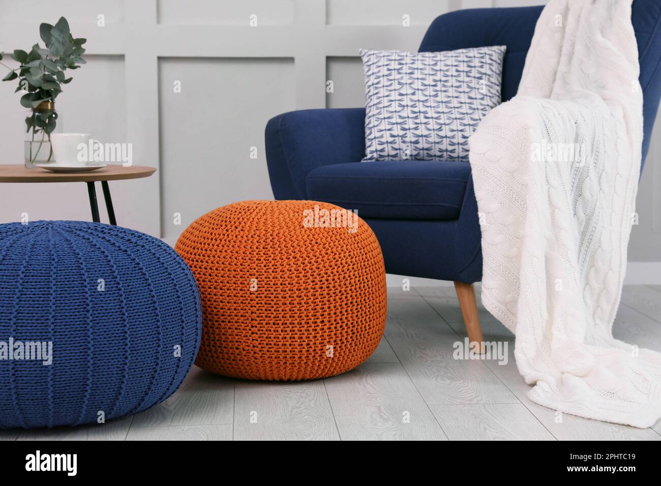Stylish knitted poufs near armchair in room. Interior design Stock ...