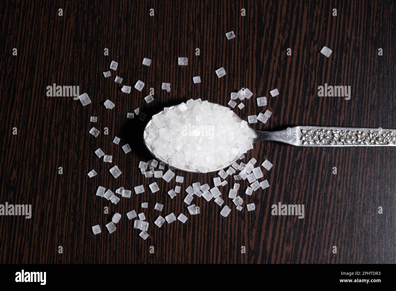 Top view of Sugar granules in spoon on the table Stock Photo
