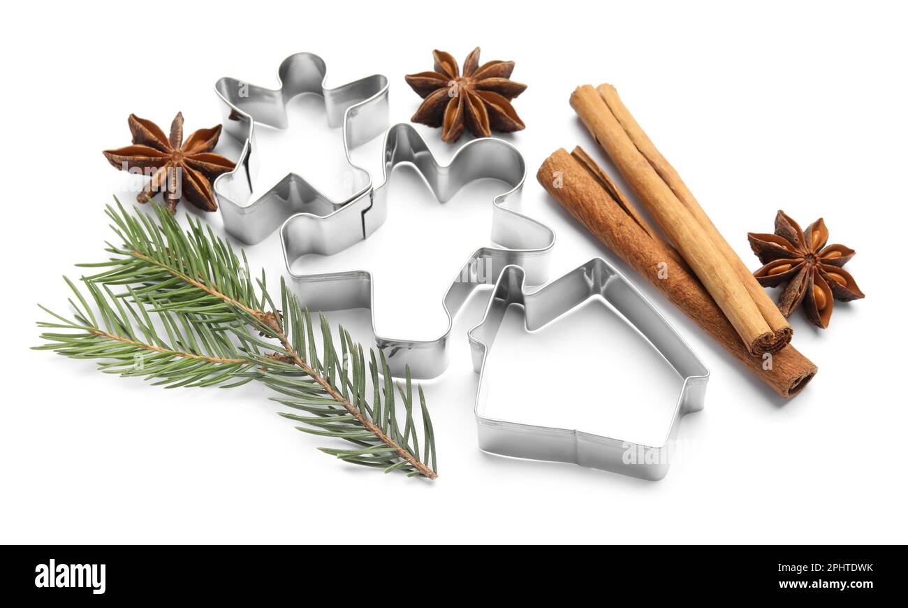 Different cookie cutters, cinnamon sticks, fir branch and anise stars on white background Stock Photo