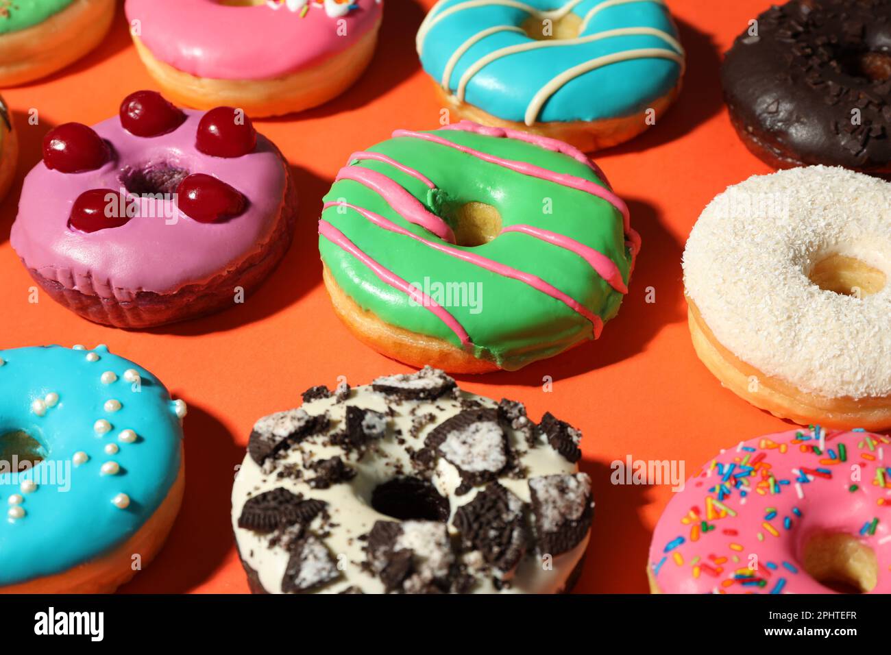 Sweet tasty glazed donuts on coral background Stock Photo