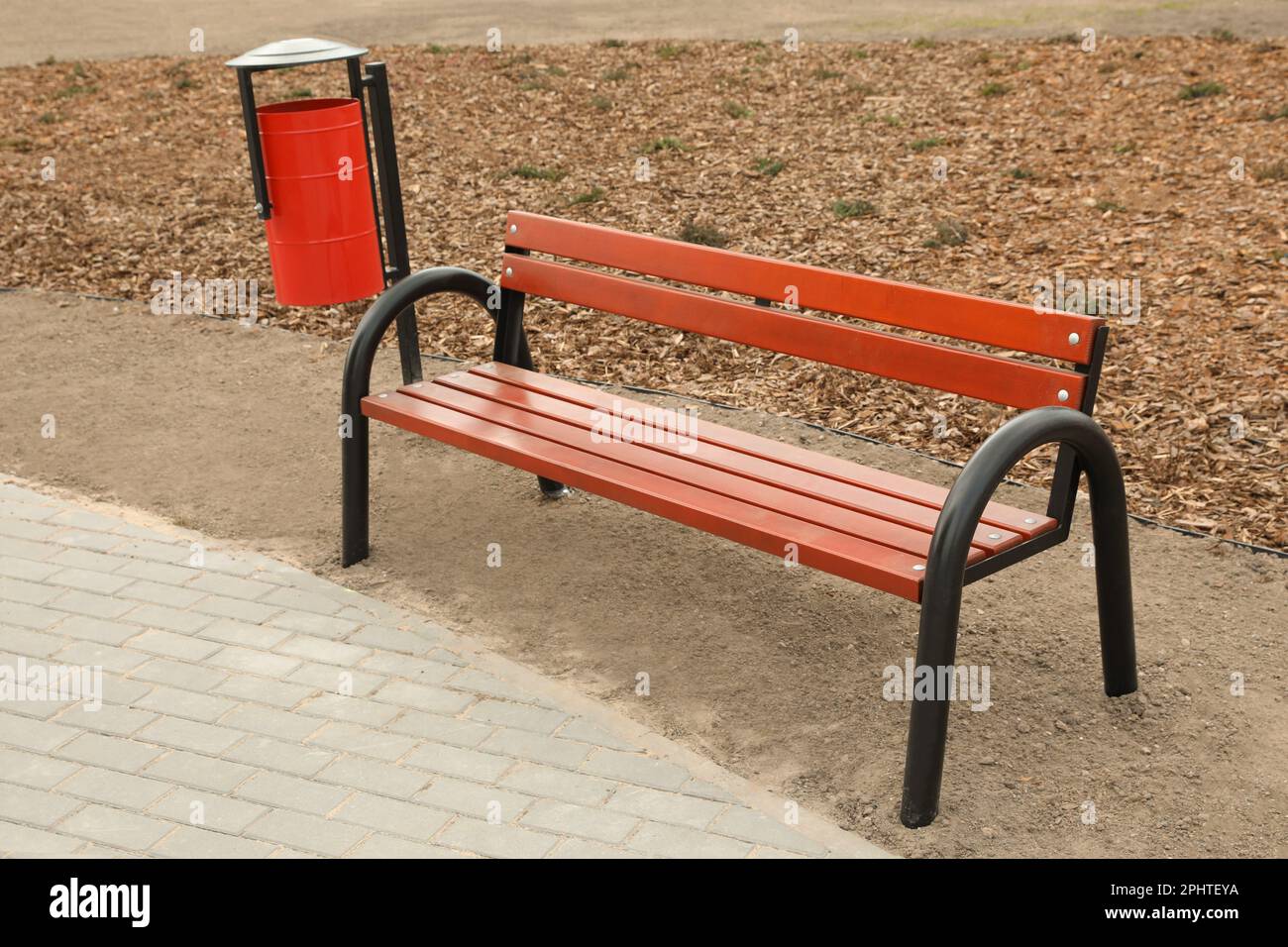 Red metal trash bin near wooden bench outdoors Stock Photo Alamy