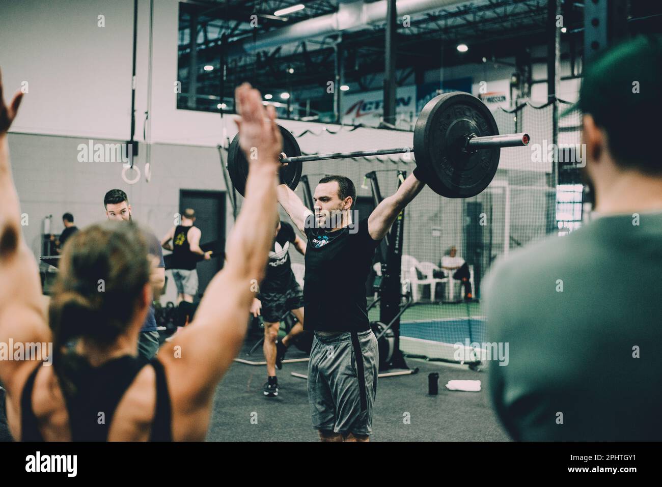 Group of athletes cheering for a man lifting barbell weights at a