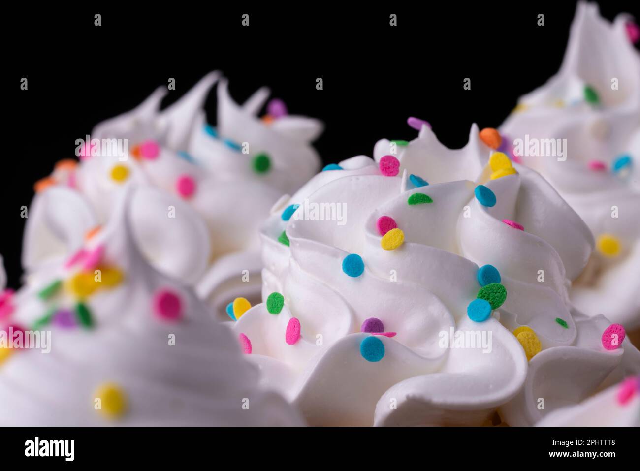Fluffy vanilla cupcakes, with meringue and dragees on a black background, original recipe Stock Photo
