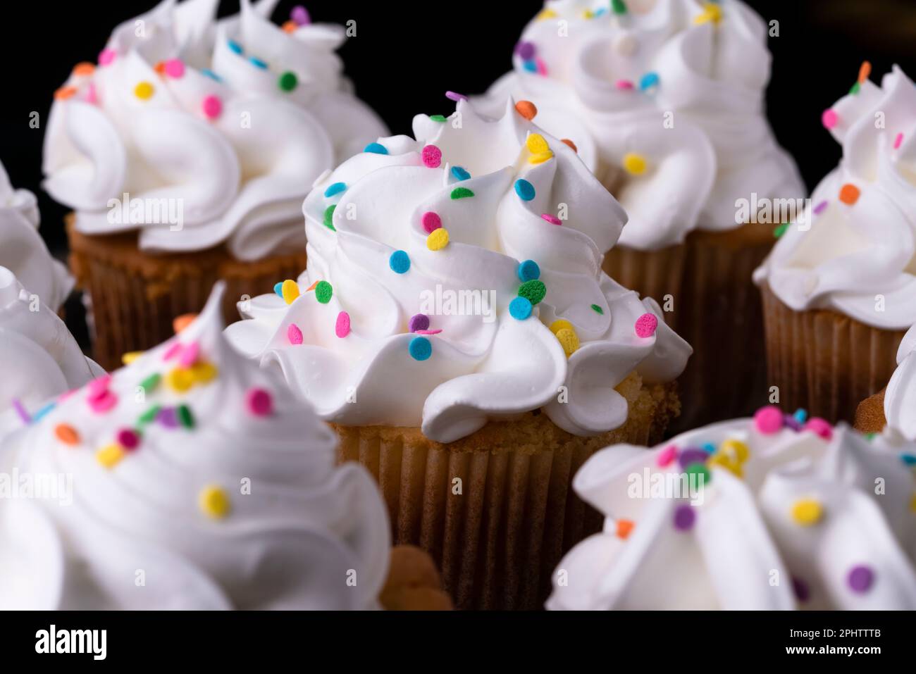 Fluffy vanilla cupcakes, with meringue and dragees on a black background, original recipe Stock Photo