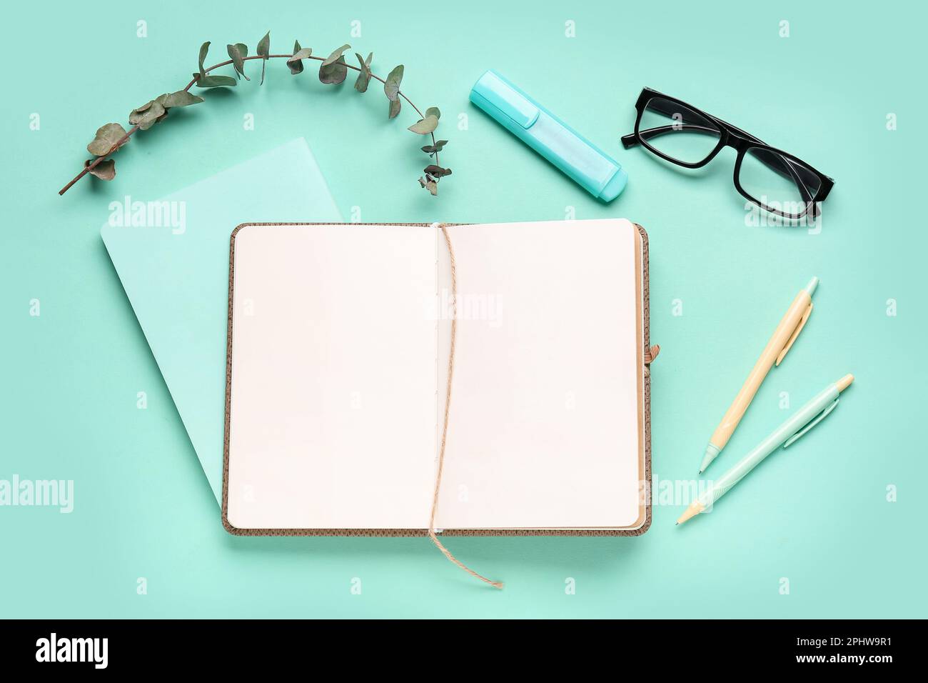 Composition with blank notebook, glasses and pens on turquoise ...