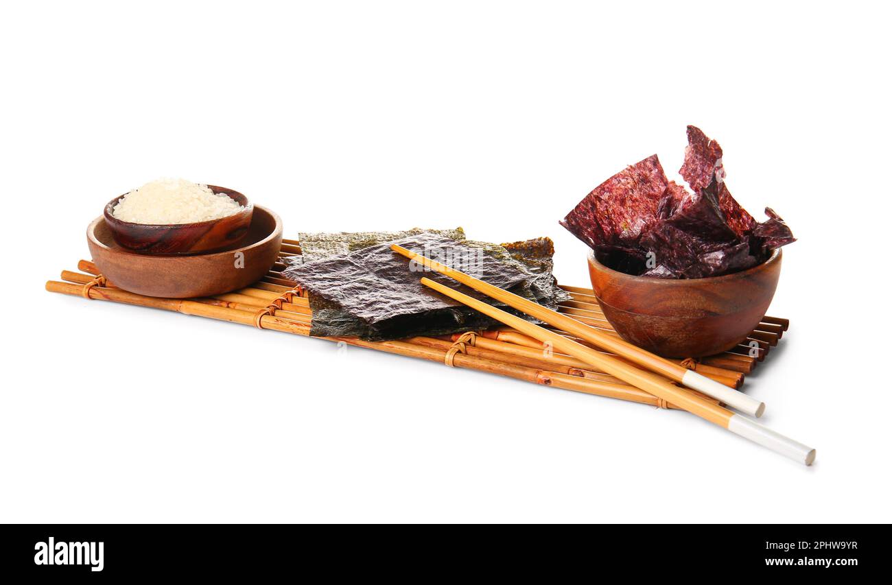 Bamboo mat with natural nori sheets, chopsticks and rice isolated on