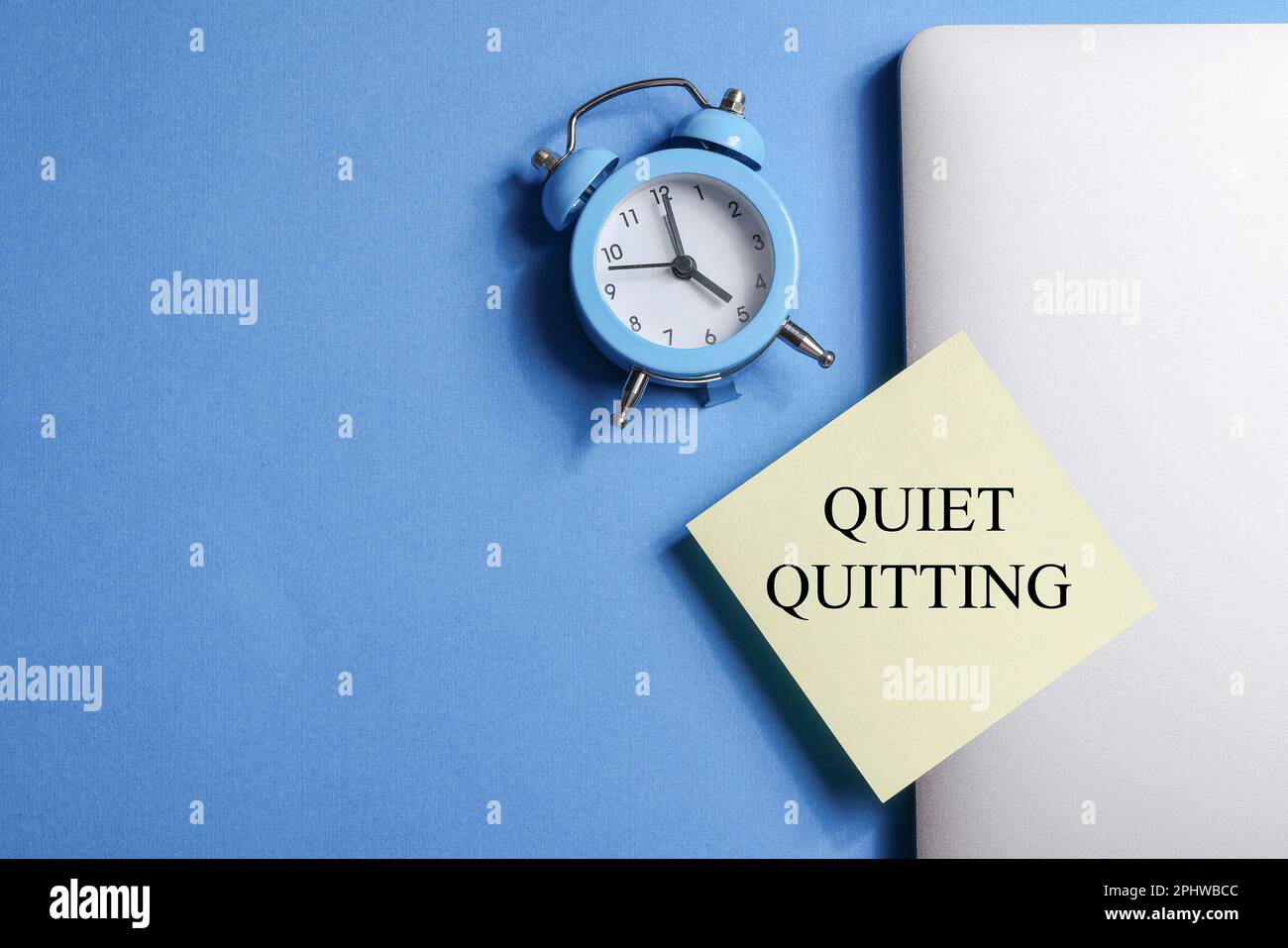 quote Quiet quitting on yellow sticker on computer with clock on blue
